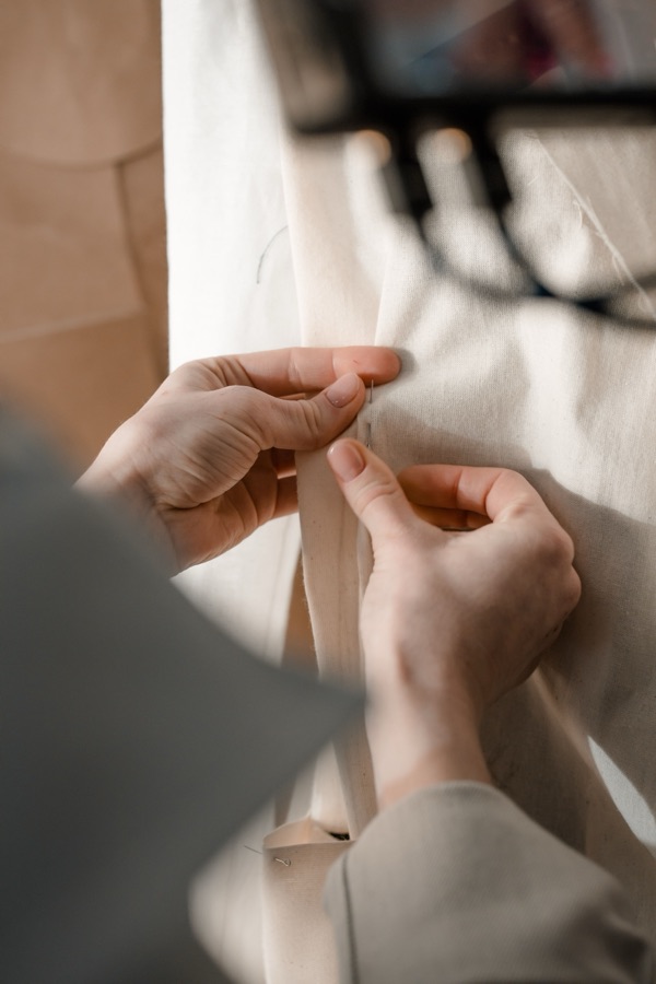 Mãos a coser à mão um tecido de linho